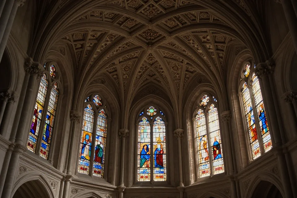 Interior del Monasterio de San Juan de los Reyes con luz natural a través de vidrieras, patrones geométricos y proporciones renacentistas